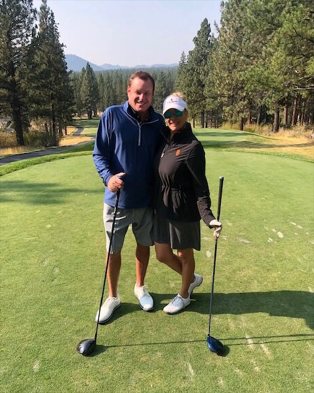 Devin Doyle and his wife standing with golf clubs on a scenic golf course.